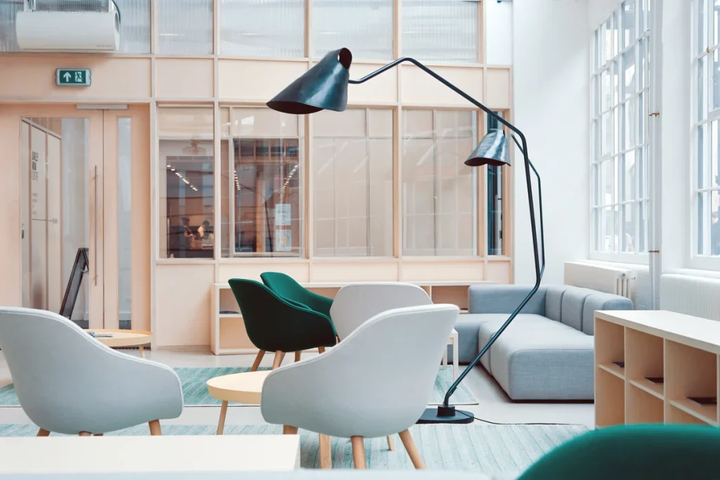 Modern office lounge with stylish upholstered chairs, contemporary fabric sofas, and elegant lighting. Featuring ergonomic seating with soft textiles in muted tones, complemented by a minimalist aesthetic. Large windows allow natural light to enhance the fabric textures, creating a welcoming and professional workspace. Ideal for discussions on office furniture materials, ergonomic design, and contemporary workspace trends.